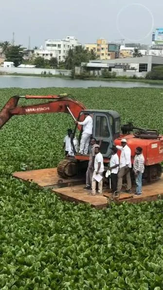 Excavator desilting a water body with water lilies before monsoon season